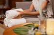 © STBSTD - Adult Asian spa employee hands arrange soft white towels client wellness treatment tranquil professional resort ambiance
