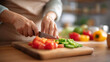 © Denis Yevtekhov - Chopping board with vegetables and hands cutting with defocused kitchen, faceless cooking scene, food preparation detail, culinary activity closeup, blurred home kitchen background