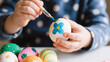 © Olia - Close-up of small child’s hands gently holding a brightly painted Easter egg, natural light highlighting tender textures and joyful holiday creativity.