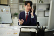 © Stella 16 - Image of handsome businessman talking on cell phone while working on computer in office