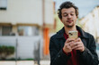 © qunica.com - A young man intently looking at his smartphone while standing outdoors, conveying focus.