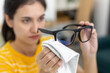 © Ratirat - Close up of young women cleaning eyeglasses with microfiber cloth, focusing on hygiene and lens care. Concept of vision clarity, daily eyewear maintenance and optical cleanliness.