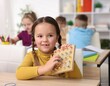 © New Africa - Smiling little girl with geoboard and rubber bands at wooden desk in elementary school