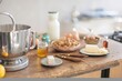 © Damian - A bright kitchen counter in the morning showcases ingredients for baking. A stand mixer sits next to bowls of nuts, eggs, butter, and a bottle of milk, ready for use