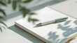 © Maha - Silver pen resting on an open notebook with lines in soft natural light
