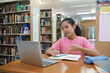 © ijeab - School student girl having video call on her computer in library at school.