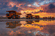 © lashkhidzetim - A group of orange dump trucks are parked on a muddy road