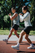 © qunica.com - A focused athletic duo performing outdoor exercises on a sunny day at a sports track.