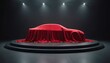 © Viktor - Red velvet cloth drapes car on circular stage with spotlights. Dramatic presentation of new model automobile under cover in studio lighting. Elegant reveal concept.