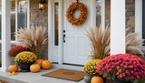 A white door and an autumn wreath, combined with pumpkins, pampas grass, and vibrant mums in black metal pots, create a cozy and welcoming ambiance on this fall porch.