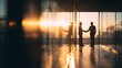 © Jojo* - Two businessmen shake hands at sunset in a modern office hallway.