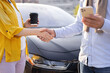 © sofiko14 - Two people shaking hands in front of a car, possibly after a business deal.