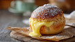 © Milon - Close up of a cream filled pastry with powdered sugar on a wooden board with a cup in background