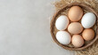 © siraphol - Fresh eggs arranged in rustic basket on straw, showcasing natural textures and colors