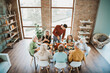 © deagreez - Family gathers around a long dinner table for a joyful Thanksgiving feast with grandparents parents kids and friends in a bright modern home