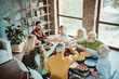 © deagreez - Family gathering around a long table for a joyful thanksgiving feast with turkey and treats in a bright cozy home