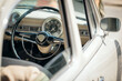 © mikelaptev - Retro dashboard with gauges, chrome, and the steering wheel of a classic car, viewed through an open side window.