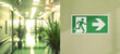 © Rioji - Fire exit sign on the right in the corridor of the office. Yellow light effect. Background space on the left for copy text.