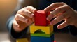 © Margarita Ratatosk - Child hands stacking colorful wooden building blocks. Kid playing with construction toy for motor skill development. Educational game for early childhood learning.