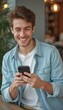 © natakot - Cheerful young man smiling while using smartphone