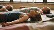 © AS - Group of people practicing yoga in a studio, lying on mats in a relaxed pose