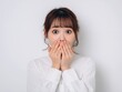 © Jumpei - 驚いた表情で口を手で押さえる白いシャツを着た若い女性の正面ポートレート写真