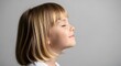 © ENDRA - A young girl with blonde hair and bangs, eyes closed and a slight smile, in profile against a plain gray background, conveying a sense of peace and contentment