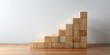 © VisualVault - Wooden blocks arranged as ascending steps on a table against a plain background, symbolizing growth and progress