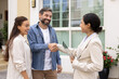 © fizkes - Happy couple handshaking with real estate agent buying house