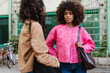 © Drobot Dean - A woman holds a bag on her shoulder and listens to a female friend standing next to her