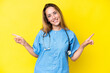 © luismolinero - Young surgeon nurse woman isolated on yellow background pointing finger to the laterals and happy