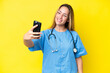 © luismolinero - Young surgeon nurse woman isolated on yellow background making a selfie