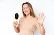 © luismolinero - Young caucasian woman with hair comb isolated on white background saluting with hand with happy expression