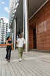 © Drobot Dean - A female worker listens to a male worker walking next to her and talking while gesturing as they carry folders