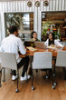 © Drobot Dean - A group of three employees sit at a table in front of laptops while one of them talks
