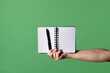 © kinomaster - A woman hand holding an open notebook and pen on a green chroma key background. Shot for designs related to office, business, education and training.