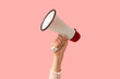 © Pixel-Shot - Female hand holding megaphone on pink background