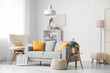 © Pixel-Shot - Interior of living room with sofa and pouf near white brick wall