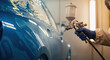 © Vyatcheslav - A professional painter sprays a blue car with a spray gun in an auto body shop. Automotive vehicle restoration and repair service. Close-up on the painting process