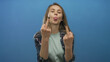© Krakenimages.com - Woman smiling confidently wearing casual blue jacket with long straight hair over plain blue background showing playful facial expression and gestures symbolizing defiance.