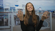 © Krakenimages.com - Woman beckons with both hands and open palms on building deck of cruise ship, smiling directly at camera; invitation joy.