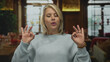© Krakenimages.com - Young blonde woman breathes calmly and holds palms facing forward in rustic restaurant building; serenity.