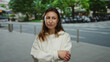 © Krakenimages.com - Woman pondering outside in an urban city street with a bus in the background under green trees showcasing a thoughtful expression on a sunny day