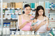 © JackF - Positive happy mother and daughter buyers at small pharmacy holding and choosing best toothbrush, scan QR code