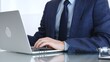© volha_r - Professional businessman working on laptop computer, typing on keyboard at modern office desk, managing business tasks. Business people concept