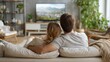 © scaliger - Cozy couple relaxing on couch watching tv in modern living room with plants, rear view