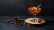 © RZ  - Elegant winter cocktail served in a vintage glass with a cinnamon stick and ice sphere, styled with pine cones and evergreen branches on a rustic wooden slice backdrop