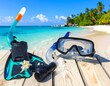 © giok - Snorkel gear on wooden planks with tropical beach in background