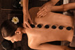 © Pixel-Shot - Beautiful young woman getting back massage with spa stones on couch in dark salon, top view