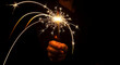 © Salman Alfarizhi - Hand holding a bright sparkler with glowing trails against a dark background.